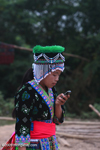 Hmong girl in traditional apparel texting on a mobile phone